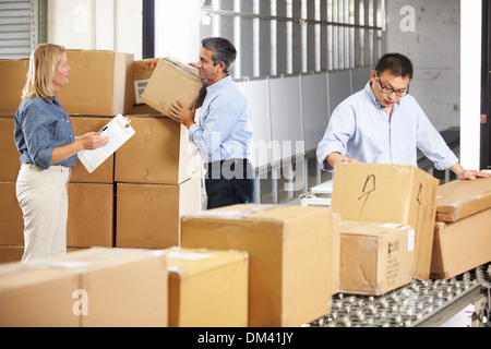 Workers Checking Goods On Belt In Distribution Warehouse Stock Photo