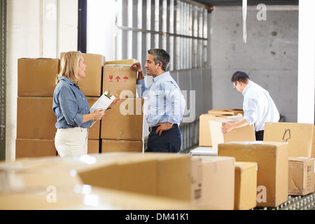 Workers Checking Goods On Belt In Distribution Warehouse Stock Photo