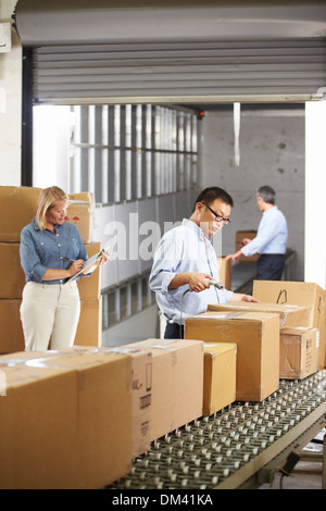 Workers Checking Goods On Belt In Distribution Warehouse Stock Photo