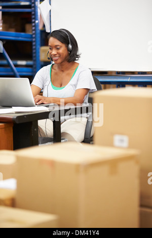 Worker In Warehouse Wearing Headset And Using Laptop Stock Photo