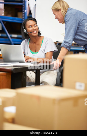 Worker In Warehouse Wearing Headset And Using Laptop Stock Photo