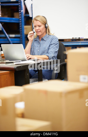 Worker In Warehouse Wearing Headset And Using Laptop Stock Photo