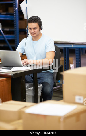 Worker In Warehouse Wearing Headset And Using Laptop Stock Photo