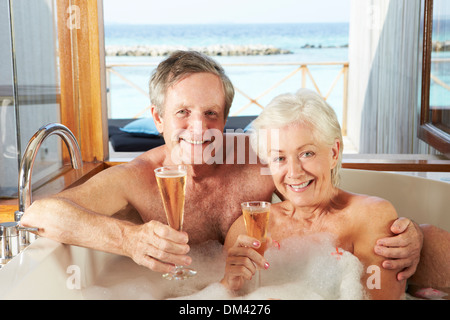 Senior Couple Relaxing In Bath Drinking Champagne Together Stock Photo