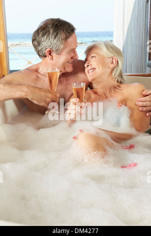 Senior Couple Relaxing In Bath Drinking Champagne Together Stock Photo