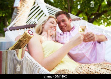 Couple Relaxing In Beach Hammock Drinking Champagne Stock Photo