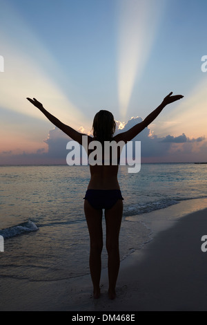 Silhouette Of Woman With Outstretched Arms On Beach Stock Photo