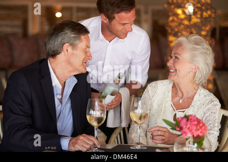 Waiter Serving Wine To Senior Couple In Restaurant Stock Photo