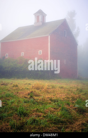 A mysterious fog surrounds an old red barn. Stock Photo