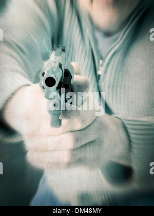 High key man firing gun at viewer in motion Stock Photo