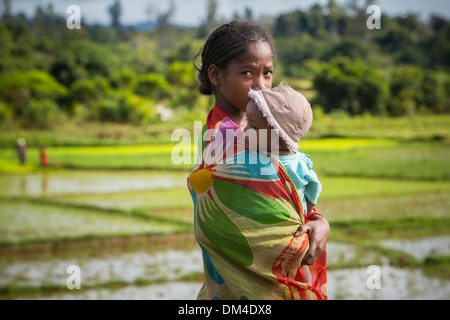 A girl holds a small child in Fenerive Est District, Madagascar. Stock Photo
