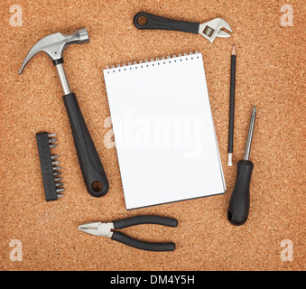 Set of tools on cork panel background with notepad for copy space Stock Photo