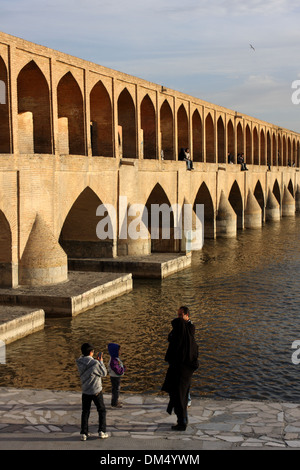 Si-o-Seh Bridge, Isfahan, Iran, with people on the bridge and in on the embankment and gulls in the sky Stock Photo