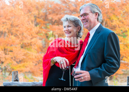 Retired couple in elegant formal outfit with dress and suit enjoying wine and each others company at outdoor party. Stock Photo