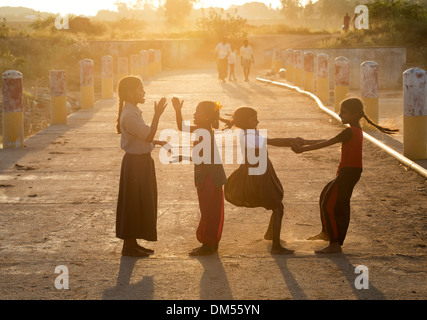 Indian girls playing on a bridge in sunlight outside their rural Indian village with lens flare. Andhra Pradesh, India Stock Photo