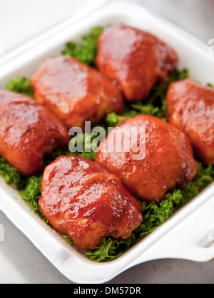 BBQ chicken thighs on a bed of parsley Stock Photo