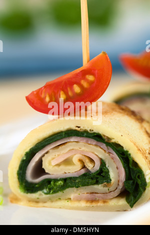 Crepe roll as finger food filled with spinach and ham garnished with cherry tomato Stock Photo