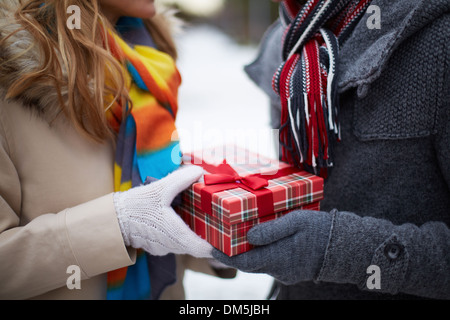 Image of gloved hand of guy giving his girlfriend Christmas present Stock Photo