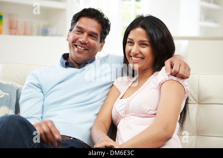 Indian Couple Sitting On Sofa Watching TV Together Stock Photo