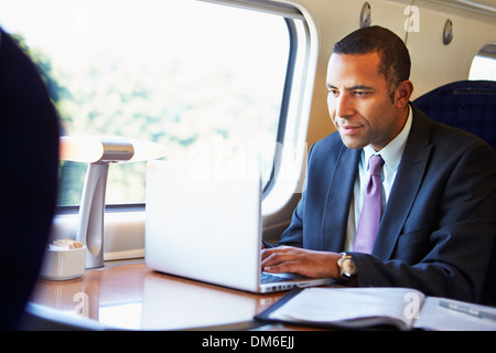 Businessman Commuting To Work On Train And Using Laptop Stock Photo