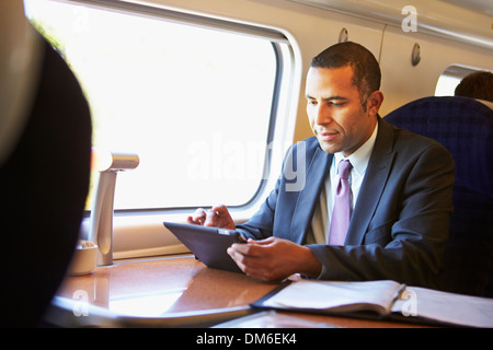 Businessman Commuting On Train Using Digital Tablet Stock Photo