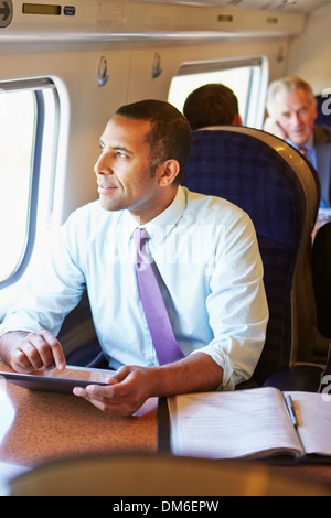 Businessman Commuting On Train Using Digital Tablet Stock Photo