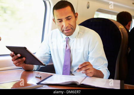 Businessman Commuting On Train Using Digital Tablet Stock Photo