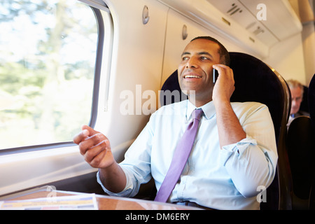 Businessman Commuting To Work On Train Using Mobile Phone Stock Photo