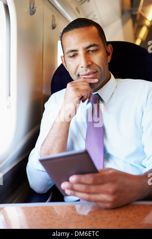 Businessman Commuting On Train Reading E Book Stock Photo