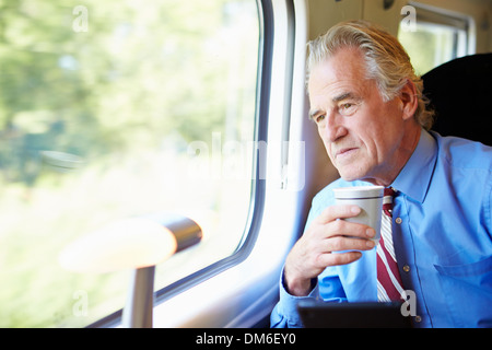 Businessman Relaxing On Train With Cup Of Coffee Stock Photo