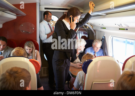 Businesswoman Using Mobile Phone On Busy Commuter Train Stock Photo