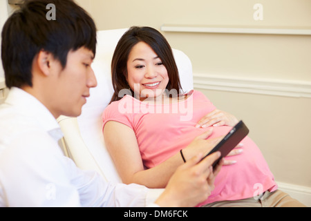 Doctor Using Digital Tablet In Meeting With Pregnant Woman Stock Photo