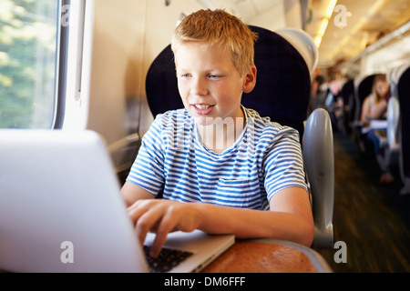 Boy Using Laptop On Train Journey Stock Photo