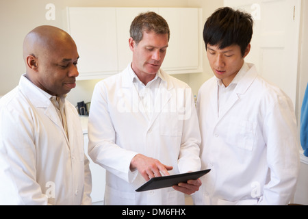 Three Doctors Having Discussion Using Digital Tablet Stock Photo