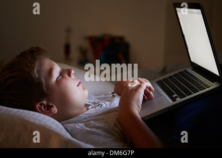 Boy Using Laptop In Bed At Night Stock Photo