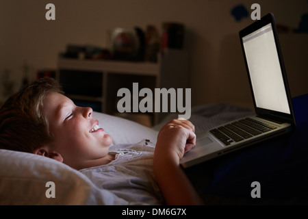 Boy Using Laptop In Bed At Night Stock Photo