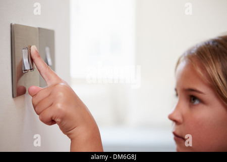 Young Girl Turning Off Light Switch Stock Photo