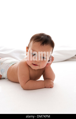 Pondering baby boy lying on the flooron white background Stock Photo