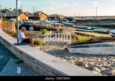 A man using his mobile phone whilst sat on a wall. Stock Photo