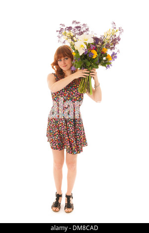 Attractive red haired girl standing with big bouquet flowers in windy studio isolated over white background Stock Photo