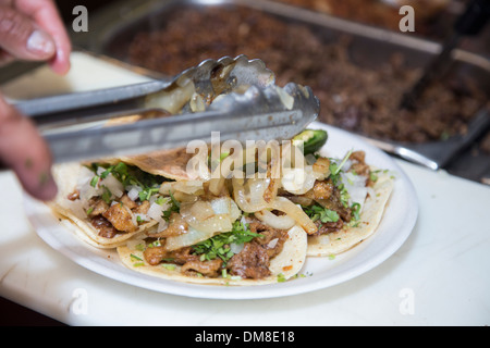 Cook putting grilled onions on fresh made chicken tacos Stock Photo
