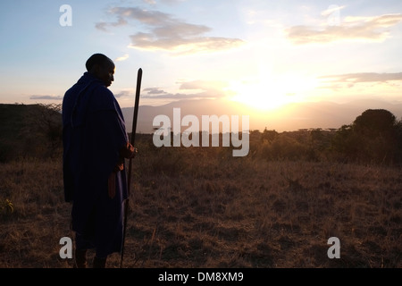 Silhouetted Maasai warrior holding a spear at the plains of the Ngorongoro Conservation Area in the Crater Highlands area of Tanzania Eastern Africa Stock Photo