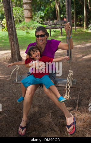 A young half Thai half American child on a swing with his grandmother - THAILAND Stock Photo