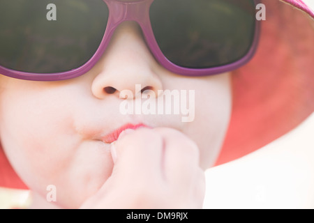 Close up of young girl with sunglasses and hat eating Stock Photo