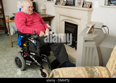 Disabled elderly man in a wheelchair watching the television Stock Photo