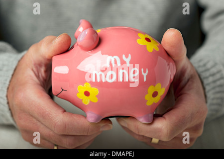 Close up of man person hand hands holding my money piggy bank pot savings investment pension person finance England UK United Kingdom GB Great Britain Stock Photo
