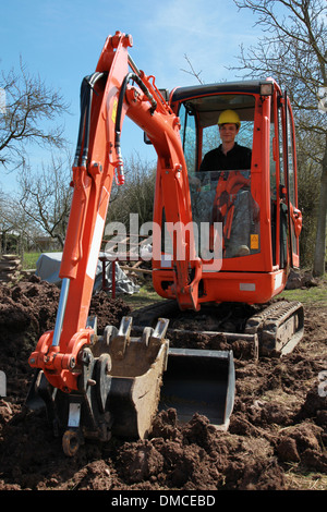 Worker sitting in an excavator in a garden Stock Photo