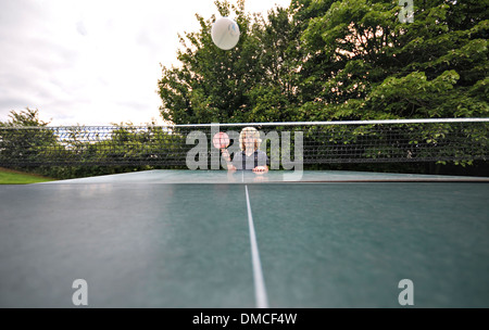 A boy plays table tennis as the ball comes back over the net Stock Photo