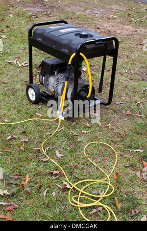 Portable electric generator with power cords attached sits on grass. Stock Photo