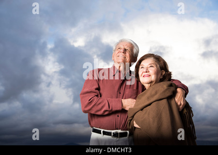 Elderly couple holding each other against a cloudy sky Stock Photo